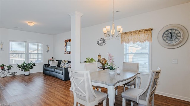 dining space featuring a wealth of natural light, an inviting chandelier, wood finished floors, and ornate columns