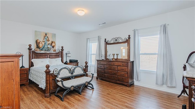 bedroom with visible vents, wood finished floors, and baseboards