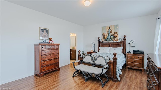 bedroom with baseboards, light wood-style flooring, and ensuite bathroom