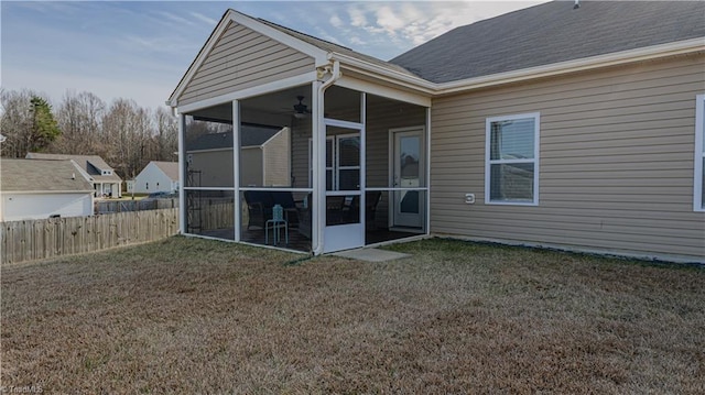 rear view of house featuring fence, a lawn, and a sunroom