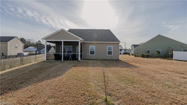 back of property with a lawn, fence, a ceiling fan, and a sunroom