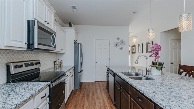 kitchen featuring light stone countertops, dark brown cabinetry, appliances with stainless steel finishes, white cabinetry, and a sink