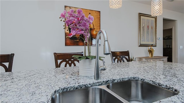 kitchen with hanging light fixtures, light stone countertops, and a sink