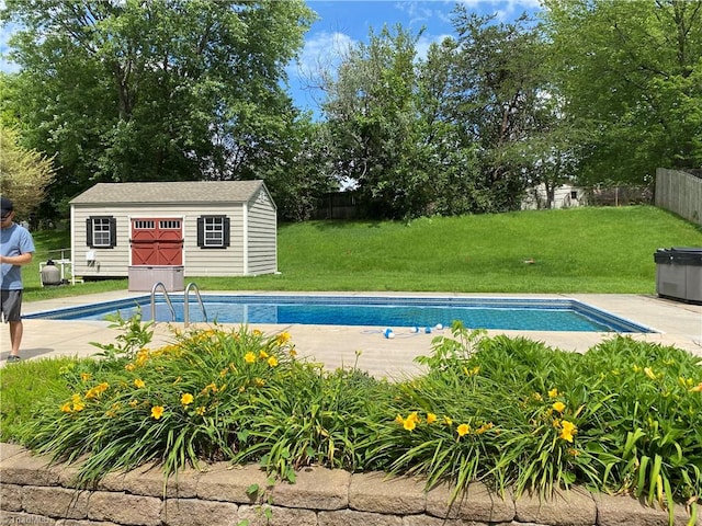 view of swimming pool with a storage shed and a lawn