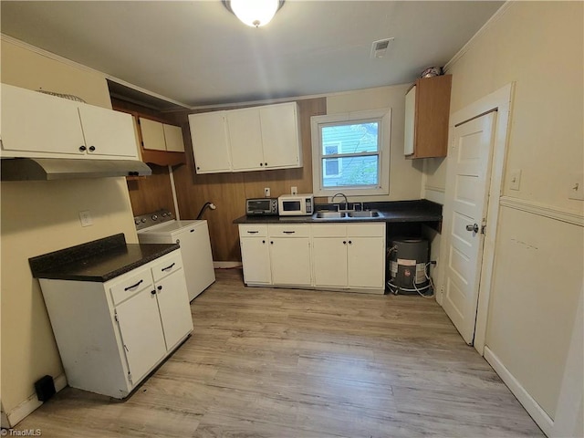 kitchen with sink, light wood-type flooring, washing machine and clothes dryer, white cabinetry, and crown molding