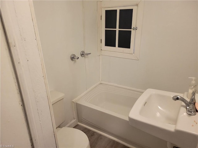 bathroom featuring sink, wood-type flooring, a tub, and toilet