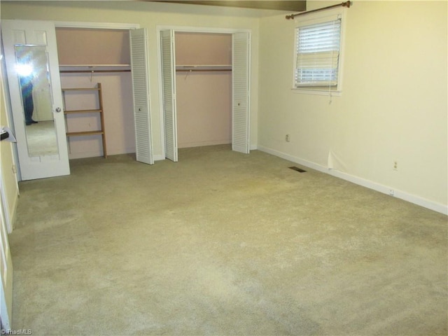 unfurnished bedroom with light carpet and multiple closets