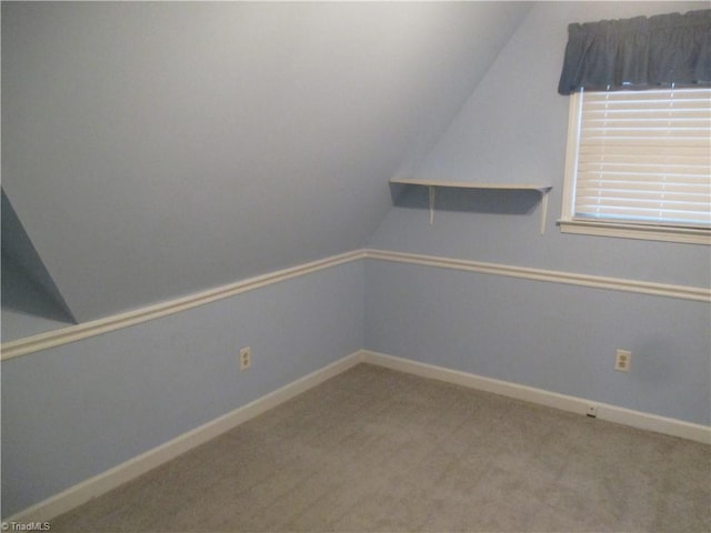 spare room featuring carpet flooring and vaulted ceiling