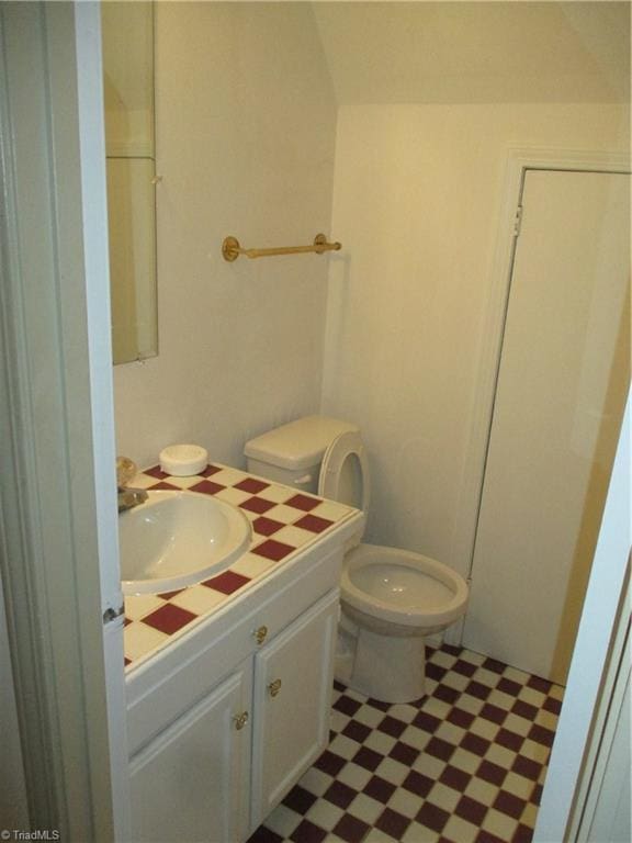 bathroom featuring vanity, lofted ceiling, and toilet