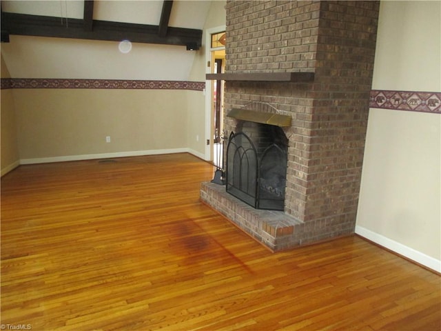 unfurnished living room with a fireplace, hardwood / wood-style floors, and lofted ceiling