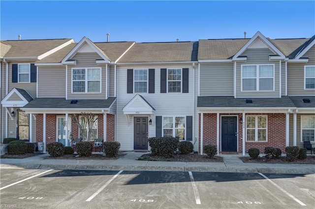 view of property with uncovered parking and brick siding