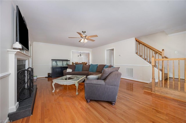 1329 Chickadee Cir, Asheboro, NC 27203 - living room featuring stairway, ceiling fan, light wood-style flooring, a fireplace with raised hearth, and baseboards