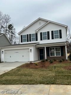 traditional home with a garage, driveway, a porch, and a front yard