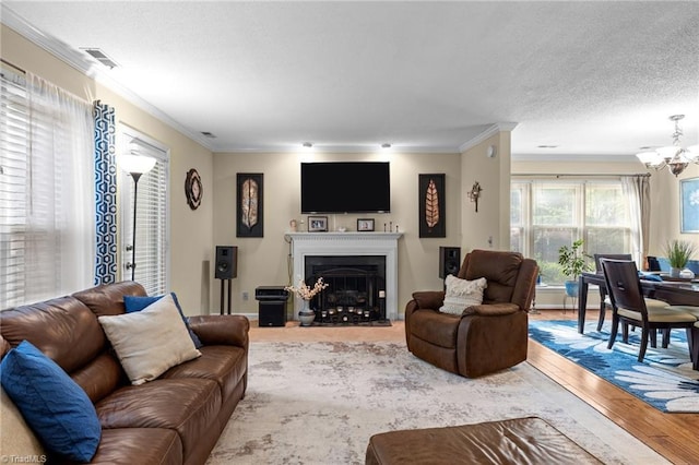 3100 Coachmans Way, Durham, NC 27705 - living room featuring wood finished floors, a chandelier, a fireplace with flush hearth, ornamental molding, and visible vents