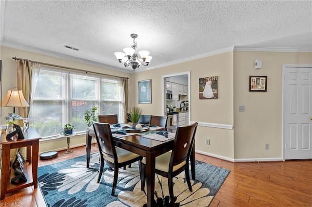 3100 Coachmans Way, Durham, NC 27705 - dining room with a textured ceiling, a chandelier, visible vents, and light wood-type flooring
