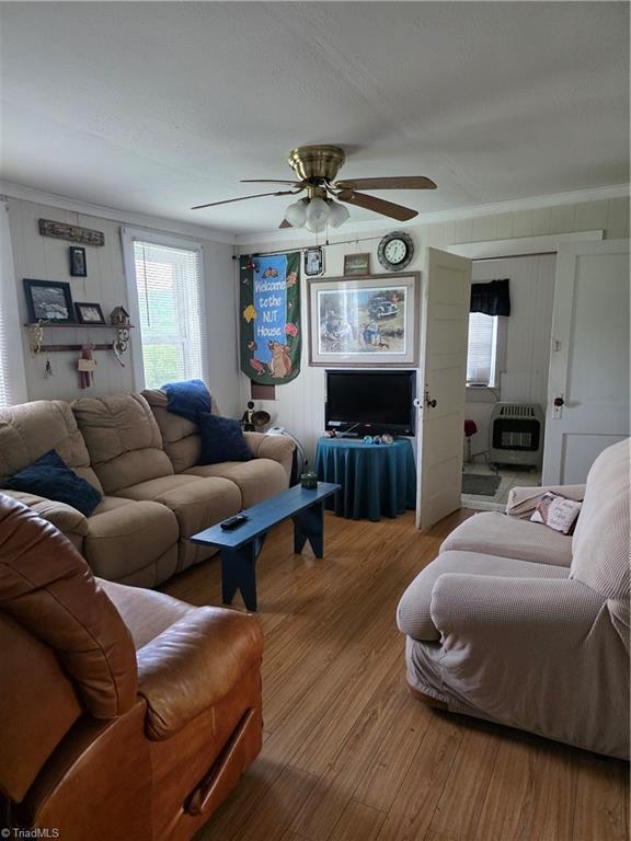 4793 Cheek Mountain Rd, Laurel Springs, NC 28644 - living area featuring ceiling fan, wood finished floors, heating unit, and crown molding