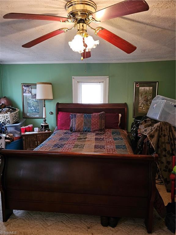 4793 Cheek Mountain Rd, Laurel Springs, NC 28644 - carpeted bedroom with ornamental molding, a ceiling fan, and a textured ceiling