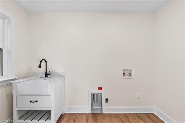 washroom with sink, light hardwood / wood-style flooring, hookup for a washing machine, cabinets, and hookup for an electric dryer