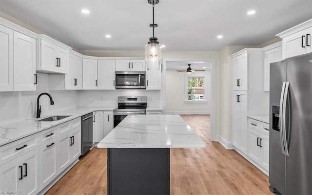 kitchen with sink, appliances with stainless steel finishes, hanging light fixtures, a center island, and white cabinets