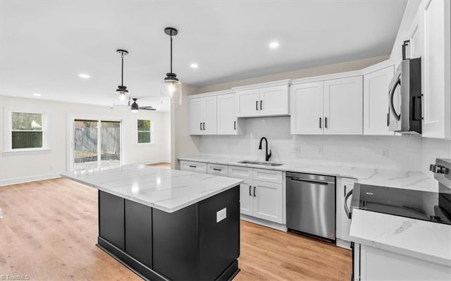 kitchen featuring sink, decorative light fixtures, appliances with stainless steel finishes, a kitchen island, and white cabinets