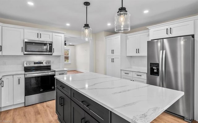 kitchen with pendant lighting, white cabinetry, stainless steel appliances, tasteful backsplash, and light wood-type flooring