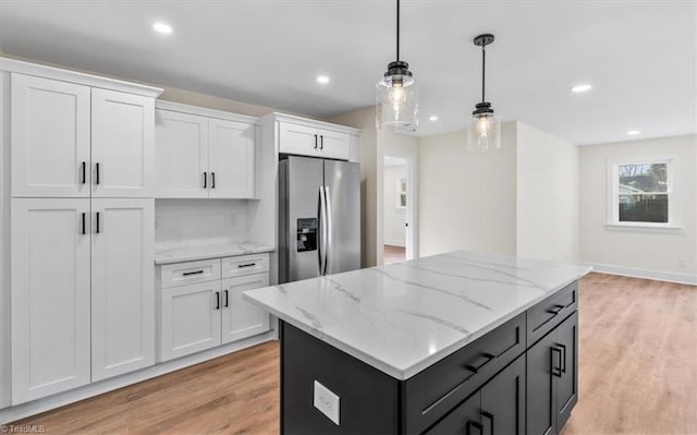 kitchen with stainless steel refrigerator with ice dispenser, white cabinetry, a center island, light wood-type flooring, and pendant lighting