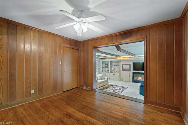 2505 Roland Rd, Greensboro, NC 27407 - unfurnished room with wooden walls, wood finished floors, built in features, a glass covered fireplace, and ceiling fan