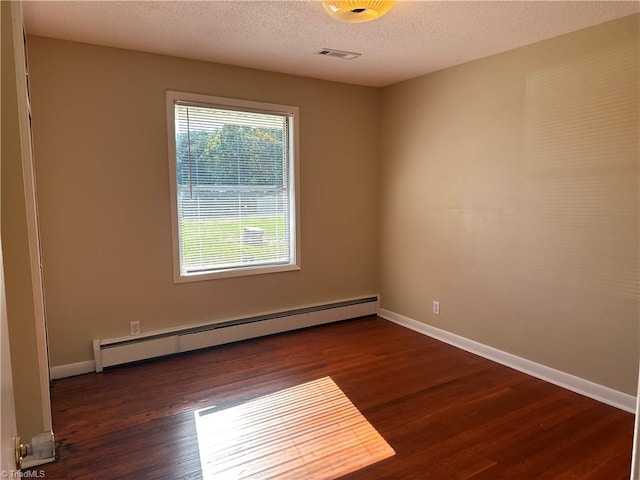 spare room featuring baseboard heating, dark wood-type flooring, and a textured ceiling