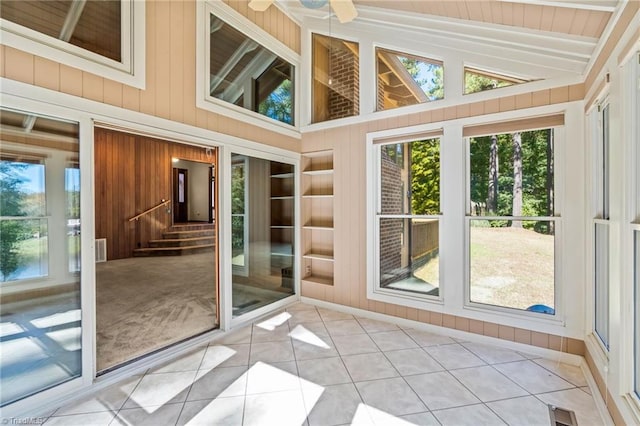 unfurnished sunroom featuring ceiling fan, lofted ceiling, and a wealth of natural light