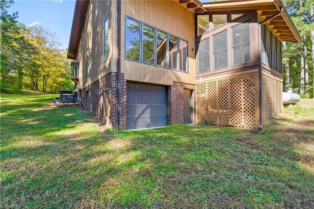 view of side of property with a yard, a sunroom, and a garage