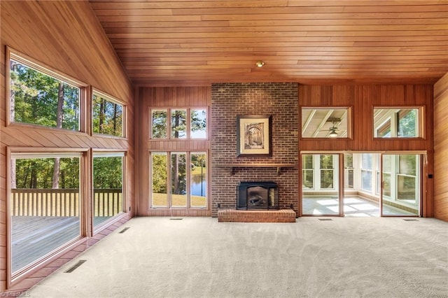 unfurnished living room with wood ceiling, wooden walls, carpet, a brick fireplace, and a water view