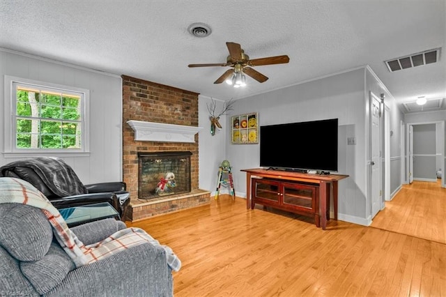 4515 Gilmore Dr, Liberty, NC 27298 - living area featuring ceiling fan, wood finished floors, crown molding, a textured ceiling, and a brick fireplace