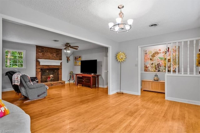 4515 Gilmore Dr, Liberty, NC 27298 - living area with light wood-type flooring, a chandelier, a textured ceiling, a brick fireplace, and baseboards