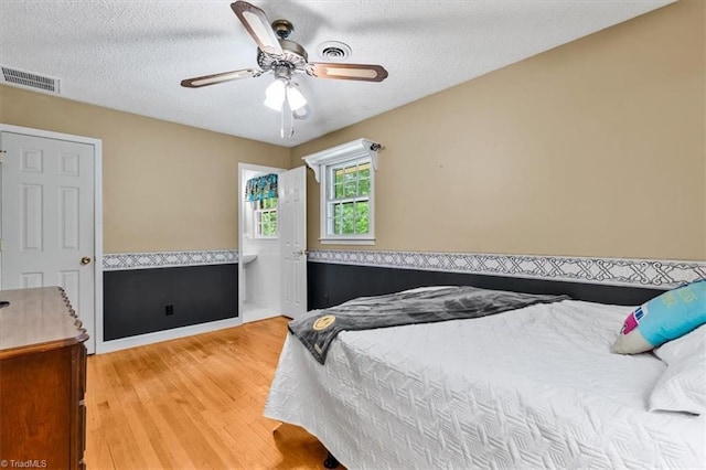 4515 Gilmore Dr, Liberty, NC 27298 - bedroom with a wainscoted wall, light wood-style floors, a textured ceiling, and a ceiling fan
