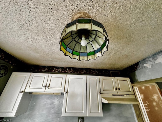 interior details with white cabinetry and a textured ceiling