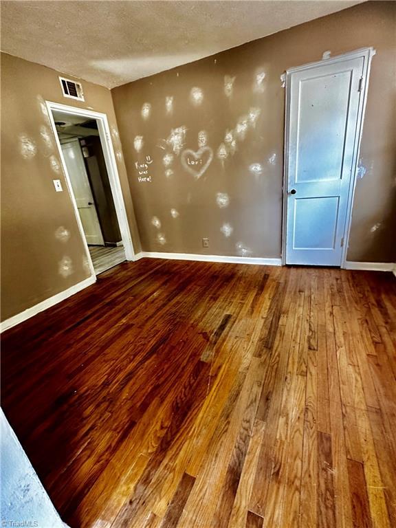 spare room featuring wood-type flooring and a textured ceiling