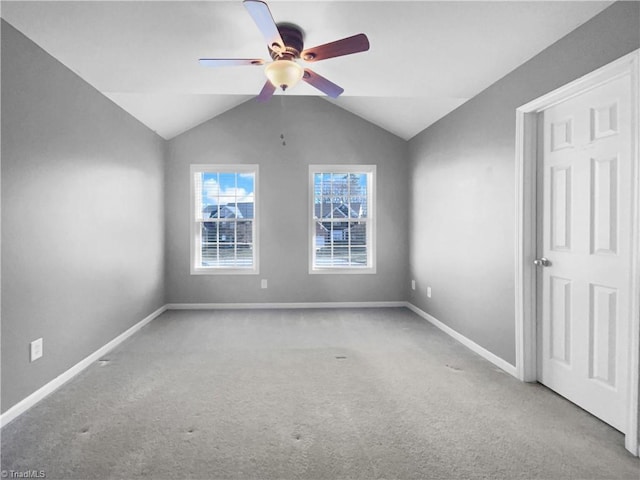 carpeted spare room featuring vaulted ceiling and ceiling fan