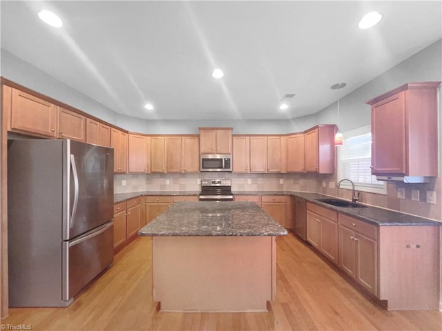 kitchen featuring stainless steel appliances, a center island, sink, and light wood-type flooring