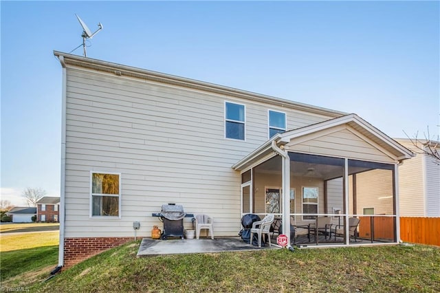 back of house featuring a sunroom, a patio, and a lawn