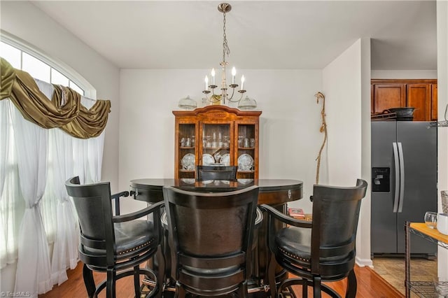 bar with stainless steel fridge with ice dispenser, pendant lighting, light wood-type flooring, and an inviting chandelier