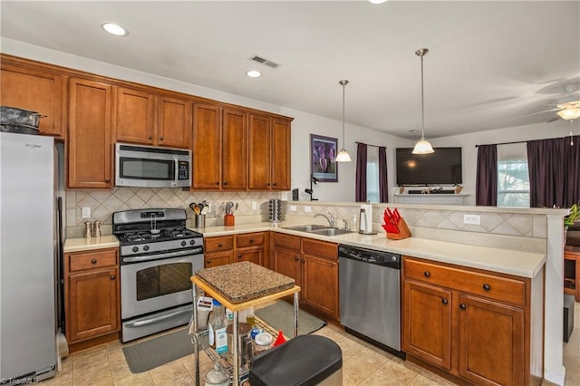 kitchen featuring kitchen peninsula, backsplash, stainless steel appliances, sink, and pendant lighting