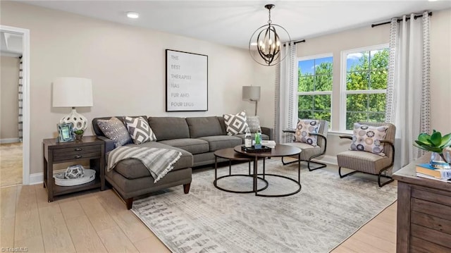 living room with plenty of natural light, light wood-type flooring, and an inviting chandelier