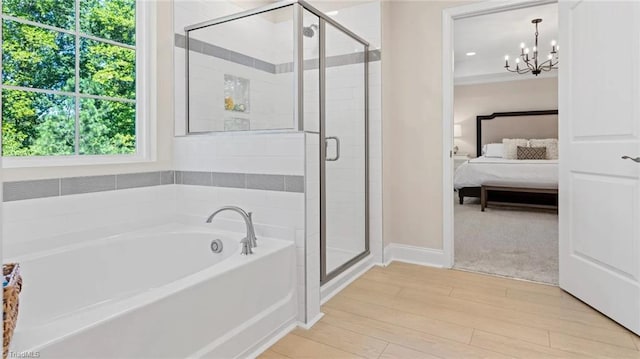 bathroom featuring hardwood / wood-style floors, independent shower and bath, and an inviting chandelier