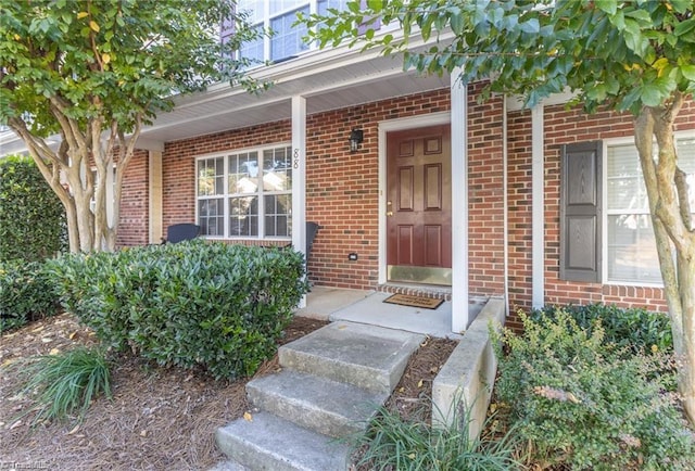 doorway to property featuring brick siding and a porch