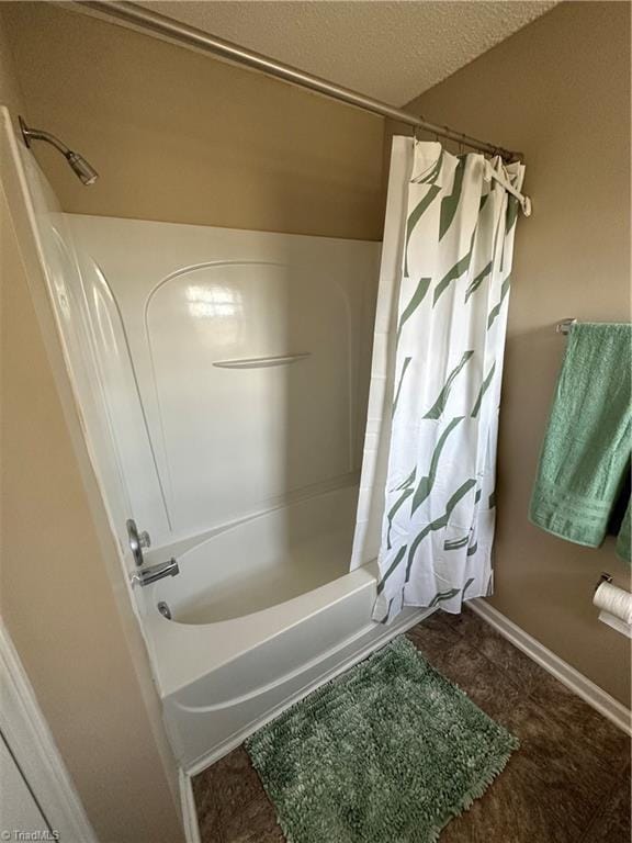 full bath featuring baseboards, shower / tub combo with curtain, and a textured ceiling