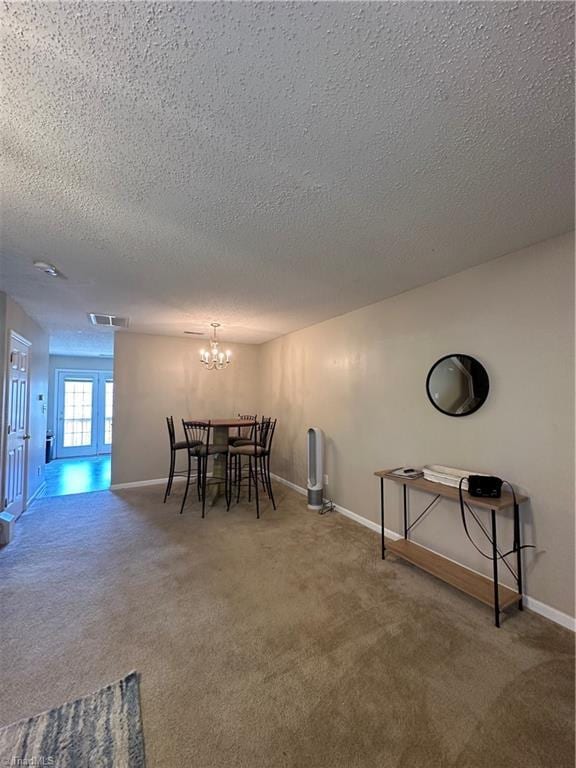 carpeted dining area with visible vents, baseboards, a notable chandelier, and a textured ceiling