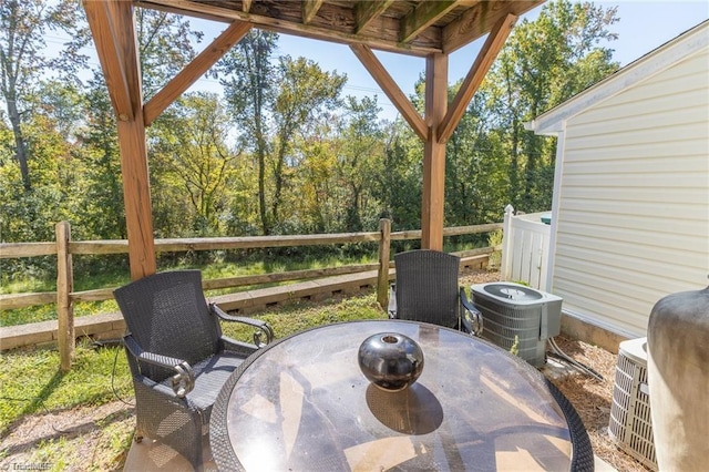 wooden terrace with outdoor dining area, central air condition unit, and fence