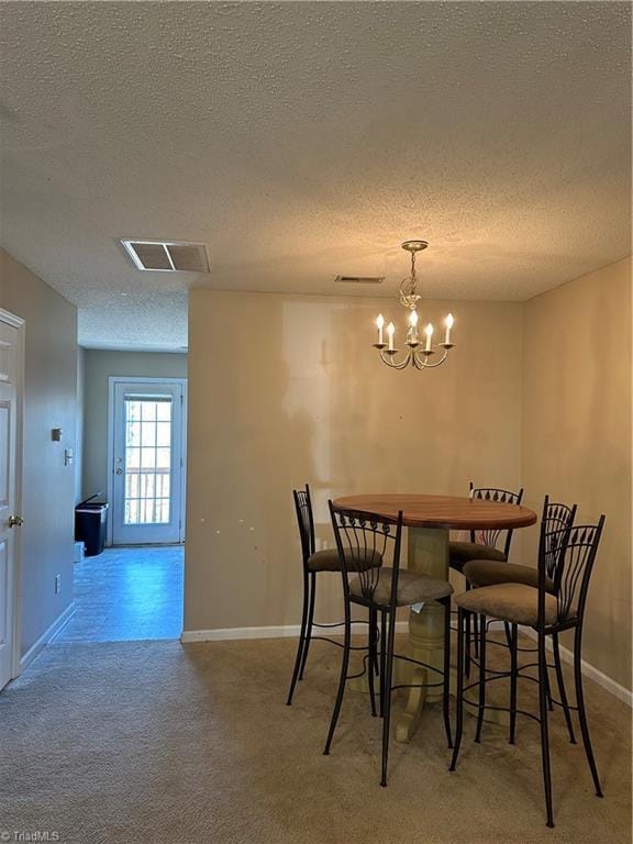 carpeted dining space featuring an inviting chandelier, baseboards, visible vents, and a textured ceiling