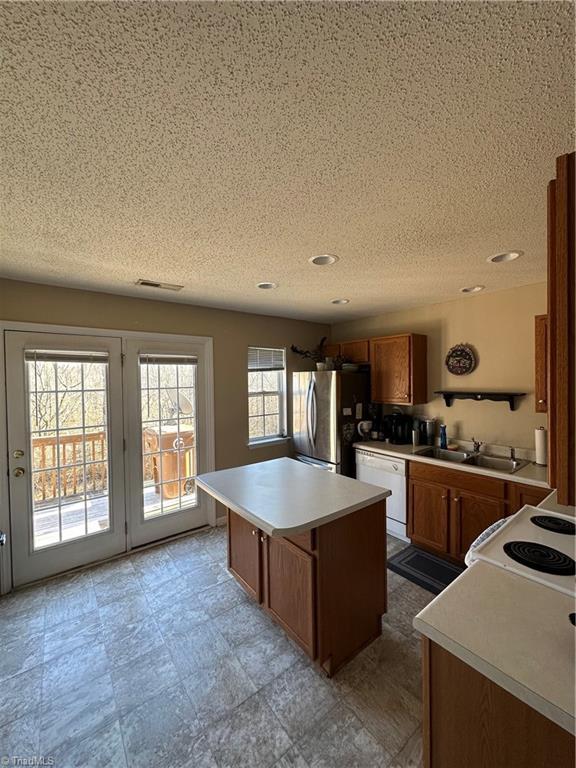 kitchen with a center island, light countertops, brown cabinets, white appliances, and a sink