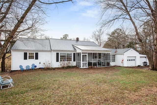 rear view of house with a garage, a sunroom, and a lawn